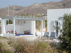 uma pérgola branca numa casa branca com duas cadeiras em Villa Aura em Kastraki