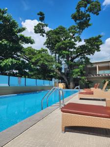 a swimming pool with two benches next to a building at The Padgett Suites in Cebu City