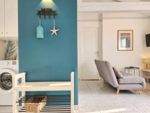 a living room with a chair and a blue wall at Maison Les Embruns avec piscine collective in La Faute-sur-Mer