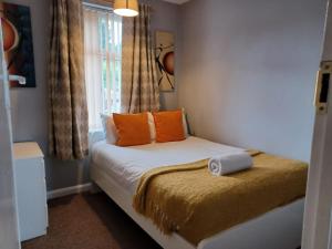 ルートンにあるMilton House - Huku Kwetu -Spacious 4 Bedroom House- Luton Airport -Group Accommodation-up to 7 peopleのベッドルーム1室(オレンジ色の枕と窓付)
