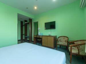 Schlafzimmer mit einem Bett, einem TV und Stühlen in der Unterkunft Royal Hotel in Keningau