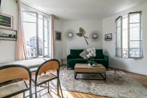 a living room with a green couch and windows at MBA Splendide Appart - Montreuil 5 - Proche Vincennes in Montreuil