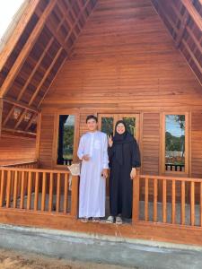 a man and woman standing in front of a wooden house at "Sakinah" Homestay Syariah AC in Sarilamak