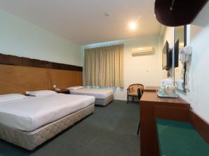 ein Hotelzimmer mit 2 Betten und einem TV in der Unterkunft Royal Hotel in Keningau