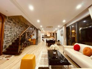 a living room with a white couch and a stone wall at An Villa Venuestay in Tam Ðảo