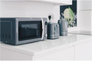 um balcão de cozinha com um micro-ondas e 2 electrodomésticos em Elegant Central Self Contained Flat by CozyNest. em Reading
