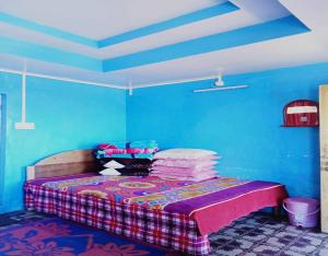 a bedroom with a bed with blue walls at Sona Homestay by StayApart in Ghum +10 photos