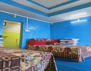 two beds in a room with blue walls at Sona Homestay by StayApart in Ghum