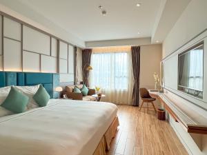 a hotel room with a large bed and a living room at Seaesta Nha Trang Hotel in Nha Trang