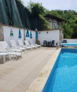 einen Pool mit weißen Stühlen und blauen Sonnenschirmen in der Unterkunft Хотел Марио in Mělník