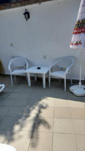 zwei weiße Bänke, ein Tisch und ein Regenschirm in der Unterkunft Хотел Марио in Mělník