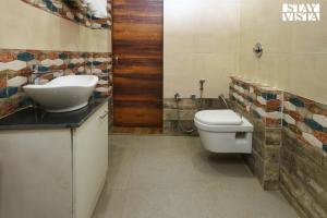 y baño con aseo blanco y lavamanos. en StayVista's Sunara Trails - Pet-Friendly, Mountainside Retreat with Balcony & Indoor-Outdoor Games - Near Panna National Park, en Panna