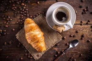 ein Croissant und eine Tasse Kaffee und Kaffeebohnen in der Unterkunft Luisella in Gaeta