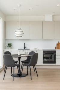 a kitchen with a table and chairs and white cabinets at Lovely Scandinavian Duplex for 6 and babybed in Vantaa Hiekkaharju Tikkurila in Vantaa