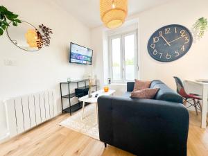 sala de estar con sofá y reloj en la pared en NEW: Agréable & lumineux *GARE*, en Guingamp