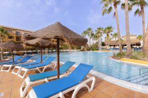 una fila di sedie a sdraio e ombrelloni accanto alla piscina di Hotel Best Alcázar a La Herradura