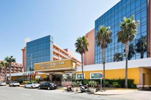 a building with palm trees and cars parked in a parking lot at Hotel Best Roquetas in Roquetas de Mar