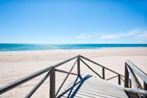 Una escalera de madera que conduce a una playa con el océano. en Hotel Best Costa Ballena, en Costa Ballena