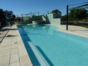 a swimming pool with blue water and a ramp at Puffers Inn in Loganholme