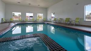 een zwembad met stoelen en tafels in een gebouw bij Best Western Palace Inn & Suites in Big Spring