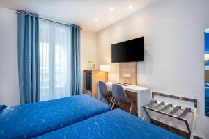 パリにあるホテル テルミヌス モンパルナスのベッド、デスク、テレビが備わるホテルルームです。