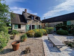 un jardín con un banco y una casa en Maison Cosy - Normandie - Haras du Pin 30', en Fay