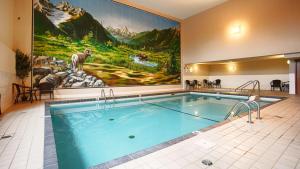 einen Pool in einem Hotelzimmer mit einem Gemälde an der Wand in der Unterkunft Prestige Radium Hot Springs Resort, WorldHotels Crafted in Radium Hot Springs