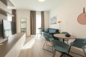 uma sala de estar com uma televisão e uma mesa e cadeiras em acora Heidelberg Living the City - Apartments em Heidelberg