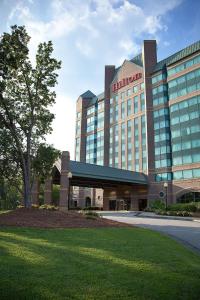 ein Hotelgebäude mit einem Baum davor in der Unterkunft Hilton Atlanta Northeast in Norcross