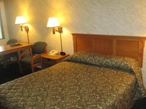 ein Hotelzimmer mit einem Bett, einem Schreibtisch und einem Telefon in der Unterkunft Bozeman Inn in Bozeman