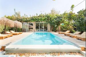 a swimming pool with lounge chairs and an apple tree at Turdus Merula Retreat in Nea Makri