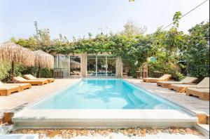 - une piscine avec des chaises longues et un pommier dans l'établissement Turdus Merula Retreat, à Nea Makri