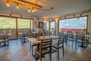 um restaurante com mesas e cadeiras e janelas grandes em Una Finestra Sulle Alpi em Bema