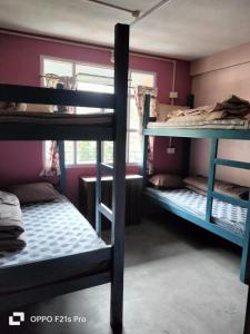 a room with three bunk beds and a window at PATHI BUNKERS in Darjeeling