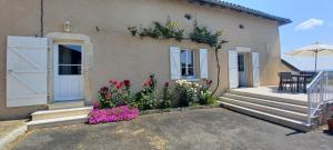 a house with a white door and some flowers at La MÉSANGE BLEUE in Écuras +9 photos