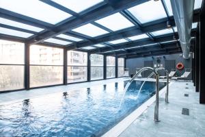 einen großen Innenpool mit Fenstern und einem großen Pool in der Unterkunft Radisson Blu Hotel Milan in Mailand