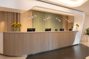 a lobby with a reception desk with chairs and flowers at Park Inn by Radisson Krakow in Krakow