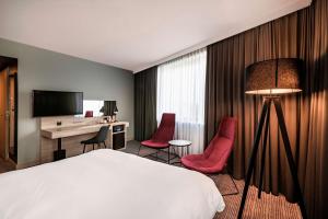 ein Hotelzimmer mit einem Bett, einem Schreibtisch und Stühlen in der Unterkunft Park Inn by Radisson Krakow in Krakau