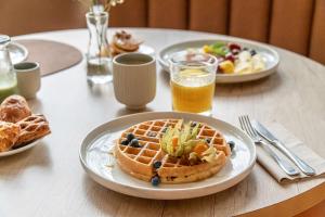 a table with a plate of waffles and a bowl of fruit at Radisson Hotel Kaunas in Kaunas