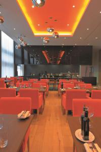 a dining room with red chairs and tables and a restaurant at Radisson Blu Hotel Zurich Airport in Kloten