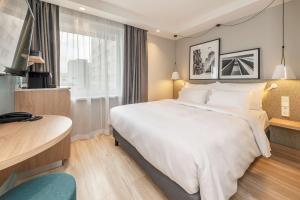 a hotel room with a large white bed and a desk at Radisson Hotel Kaunas in Kaunas