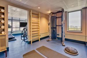 a fitness room with a gym with a treadmill and weights at Hôtel Aiden by Best Western Clermont-Ferrand - Le Magnetic in Clermont-Ferrand