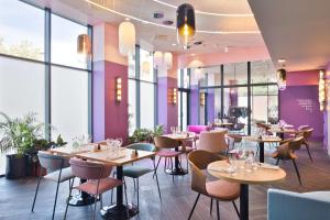 a restaurant with tables and chairs and windows at Aiden by Best Western Clermont-Ferrand - Le Magnetic Hotel & Spa in Clermont-Ferrand