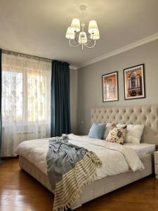 阿拉木圖的住宿－Уютная квартира в центре Алматы с потрясающими видами，一间卧室配有一张大床和一个吊灯。