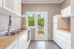 a white kitchen with a sink and a window at Casa a metros del Mar in Playa de Muro