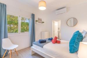 a bedroom with a bed and a chair and a window at Casa a metros del Mar in Playa de Muro