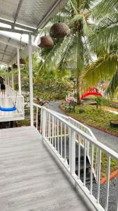 a porch with a white railing and palm trees at Homestay Cô Hai Garden in Ấp Vĩnh Hưng