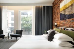 a bedroom with a white bed and a brick wall at The Alexis Royal Sonesta Hotel Seattle in Seattle