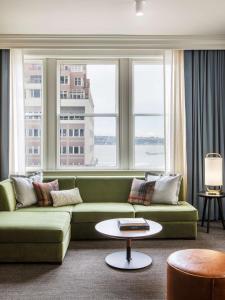 a living room with a green couch and windows at The Alexis Royal Sonesta Hotel Seattle in Seattle