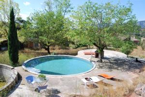 uma piscina num quintal com cadeiras e árvores em Masia Vilatersana em Sant Llorenc Savall